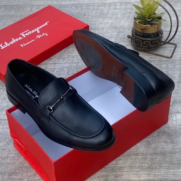 A pair of luxurious black Salvatore Ferragamo loafers, one placed inside a red shoe box and the other beside it, showcasing the high-quality leather and sleek design.