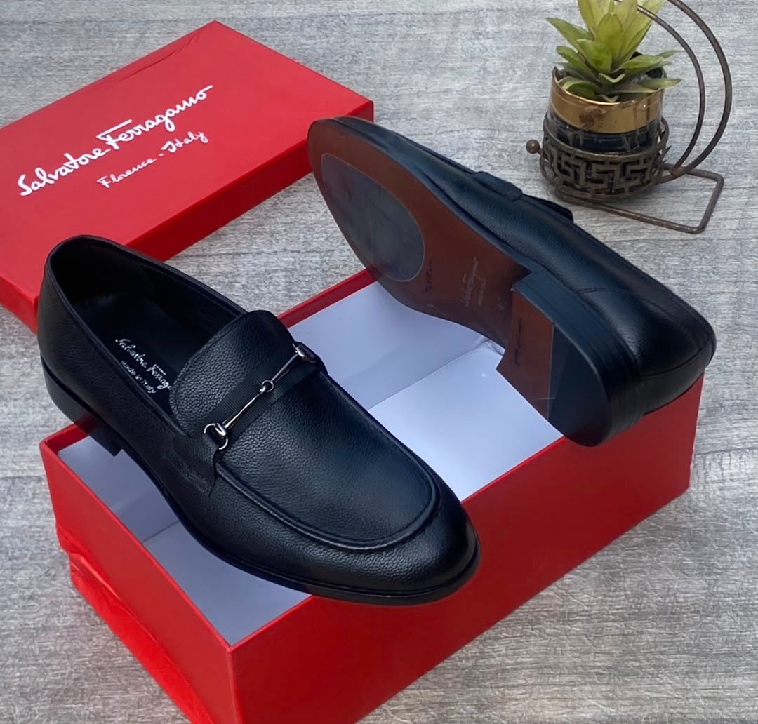 root A pair of luxurious black Salvatore Ferragamo loafers, one placed inside a red shoe box and the other beside it, showcasing the high-quality leather and sleek design.