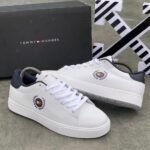 A pair of luxurious white Tommy Hilfiger sneakers with navy accents and logo detailing, displayed with their original box.