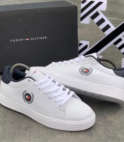 A pair of luxurious white Tommy Hilfiger sneakers with navy accents and logo detailing, displayed with their original box.