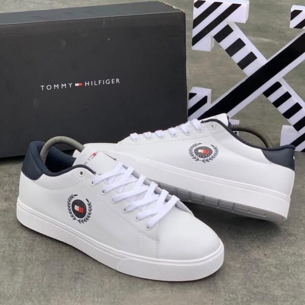 A pair of luxurious white Tommy Hilfiger sneakers with navy accents and logo detailing, displayed with their original box.