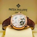 Exquisite Patek Philippe watch with white dial and brown leather strap, showcasing intricate mechanical details.