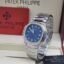 A luxurious Patek Philippe watch with a blue face and diamond-encrusted bezel, presented in an elegant box.