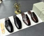 A pair of luxurious black leather half shoes displayed on a white surface, and a decorative gold ship's wheel, exuding elegance and refinement.