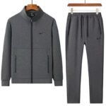 A stylish grey tracksuit consisting of a zip-up jacket and matching joggers, both featuring the Nike logo, displayed on hangers against a white background.