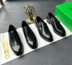 A pair of luxurious black leather oxford shoes with brogue detailing, presented on a crisp white background with a green box and golden accents, evoking a sense of high-end style and sophistication.