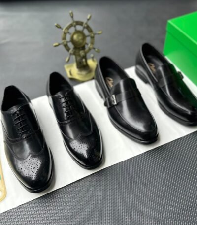 A pair of luxurious black leather oxford shoes with brogue detailing, presented on a crisp white background with a green box and golden accents, evoking a sense of high-end style and sophistication.