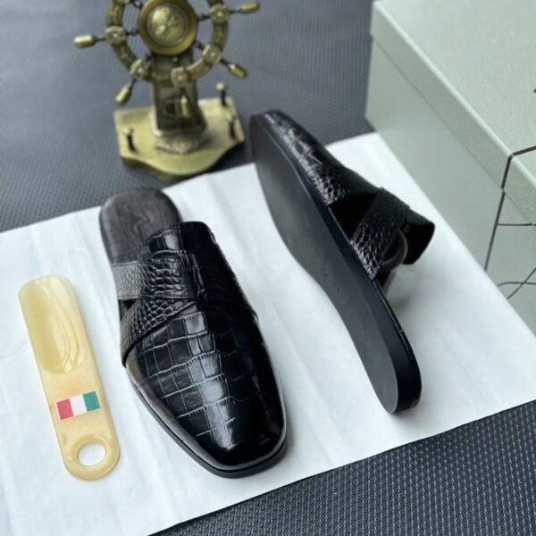A pair of luxurious black leather half shoes displayed on a white surface, and a decorative gold ship's wheel, exuding elegance and refinement.
