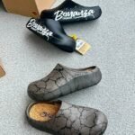A pair of stylish clogs in black and grey marble finish, showcasing the brand name and logo.