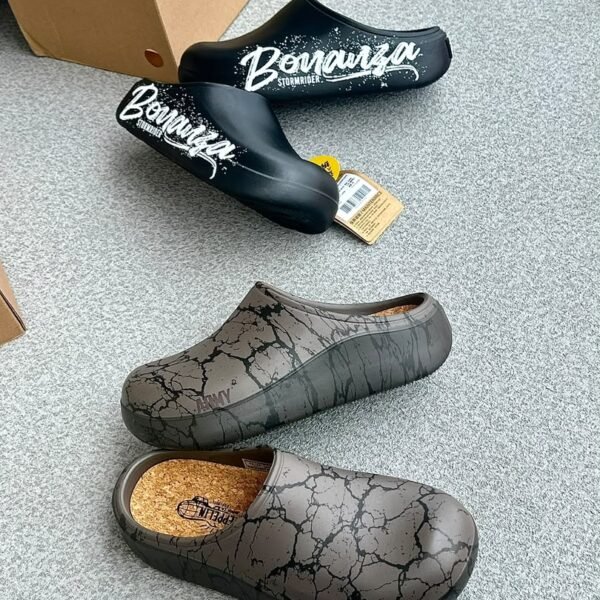 A pair of stylish clogs in black and grey marble finish, showcasing the brand name and logo.