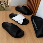Luxurious slides in black and white, presented on a wooden table with a black bag bearing the Cesare Paciotti logo.