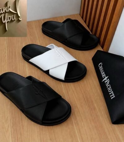 Luxurious slides in black and white, presented on a wooden table with a black bag bearing the Cesare Paciotti logo.