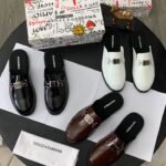 A luxurious display of Dolce & Gabbana loafers in black, brown, and white, accompanied by the brand's signature box and cloth.