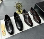 A pair of black leather monk strap shoes on a white cloth, accompanied by a shoe tree and a decorative ship's wheel, exuding luxury and refinement.